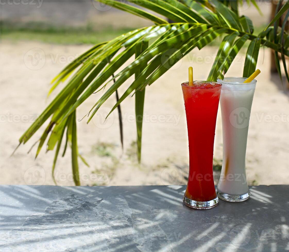 Tequila sunrise and pina colada cocktails under the palm photo