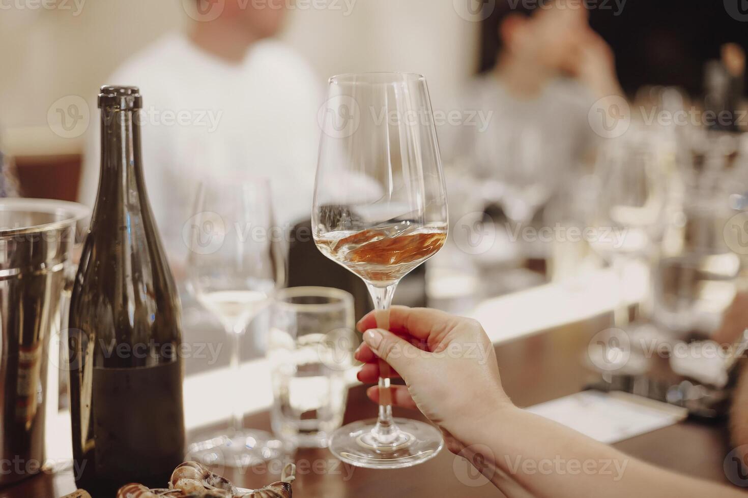 Glasses with different types of wine and human hands holding wine glasses in the background photo