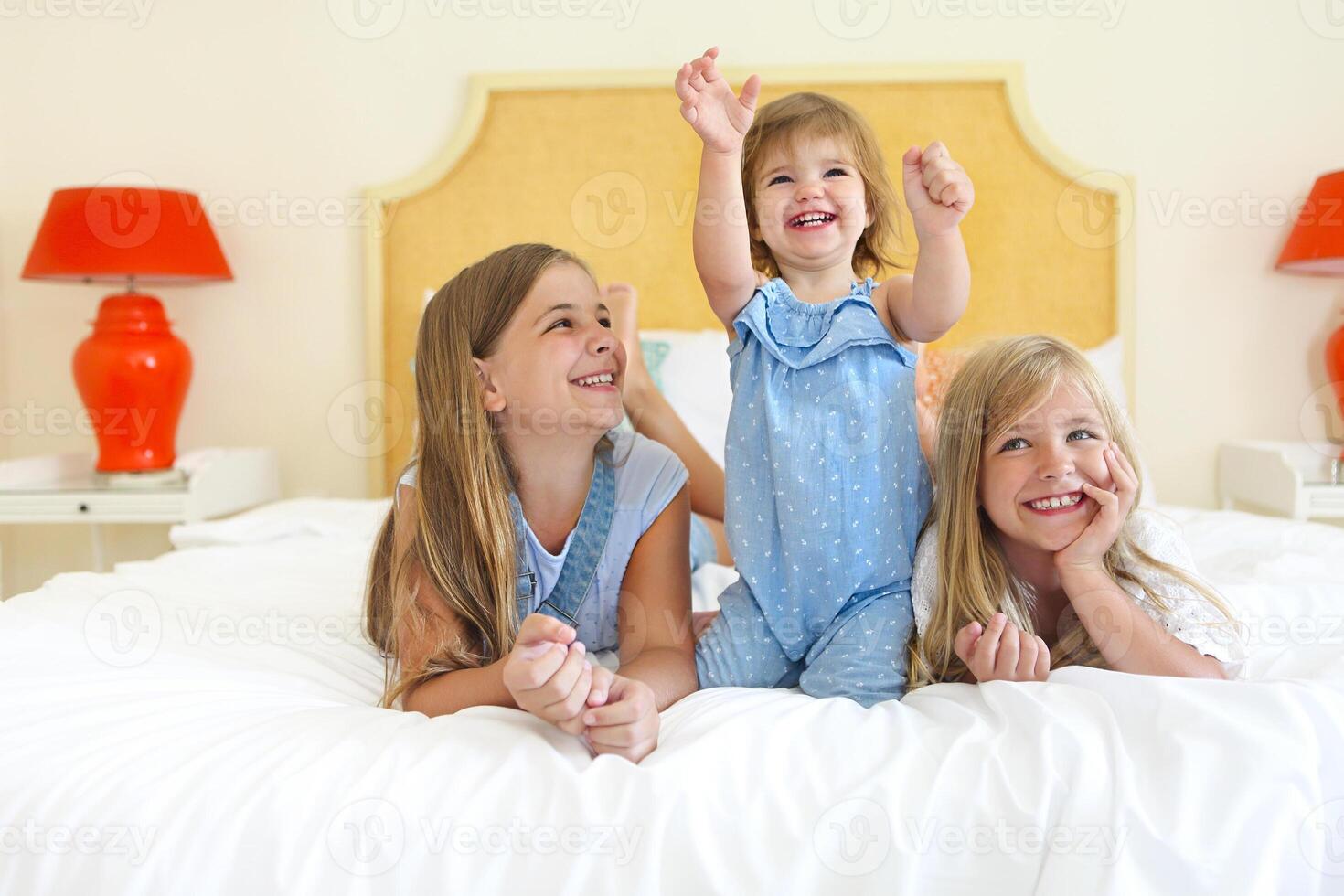 Three little sisters on a bed having fun photo