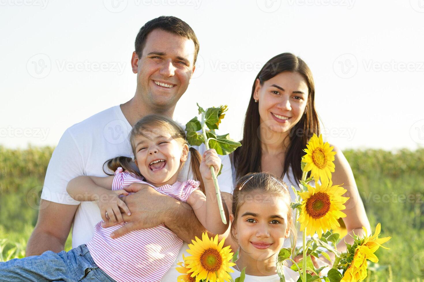 Cheerful family with sunflowers in field photo