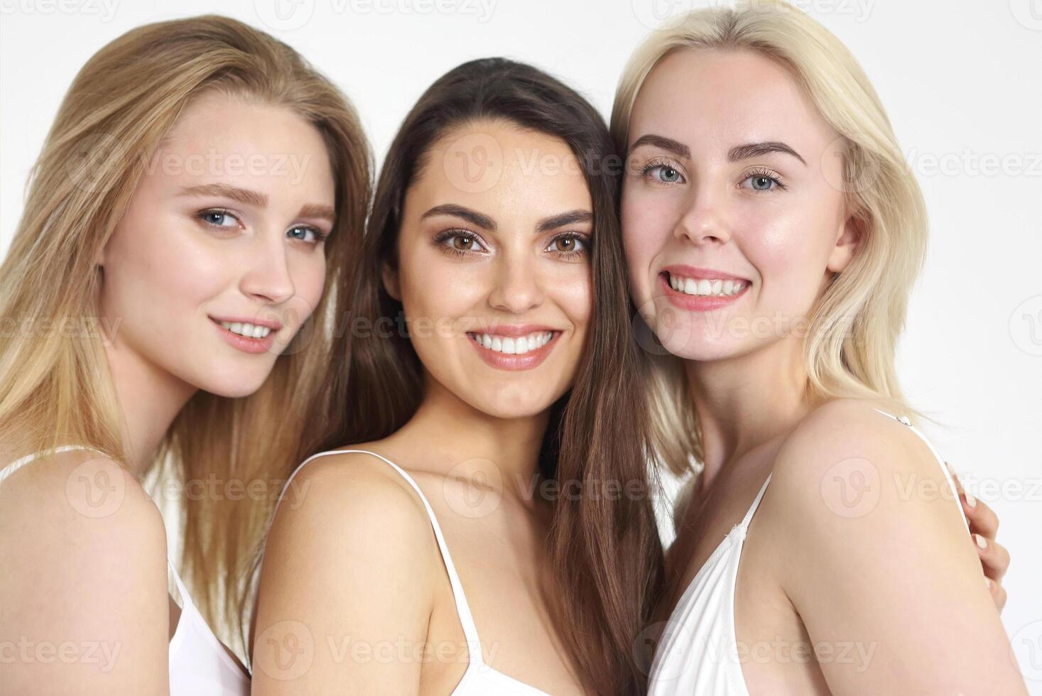 Group of happy different women in white hugging over white background. photo