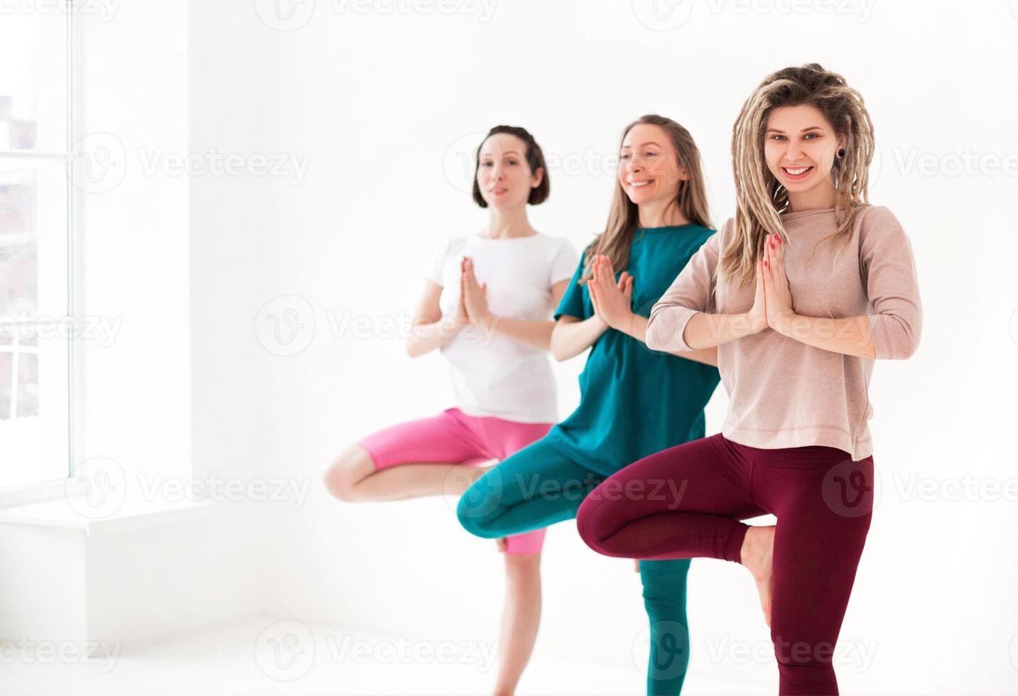 Cheerful young girlfriends meditating together photo