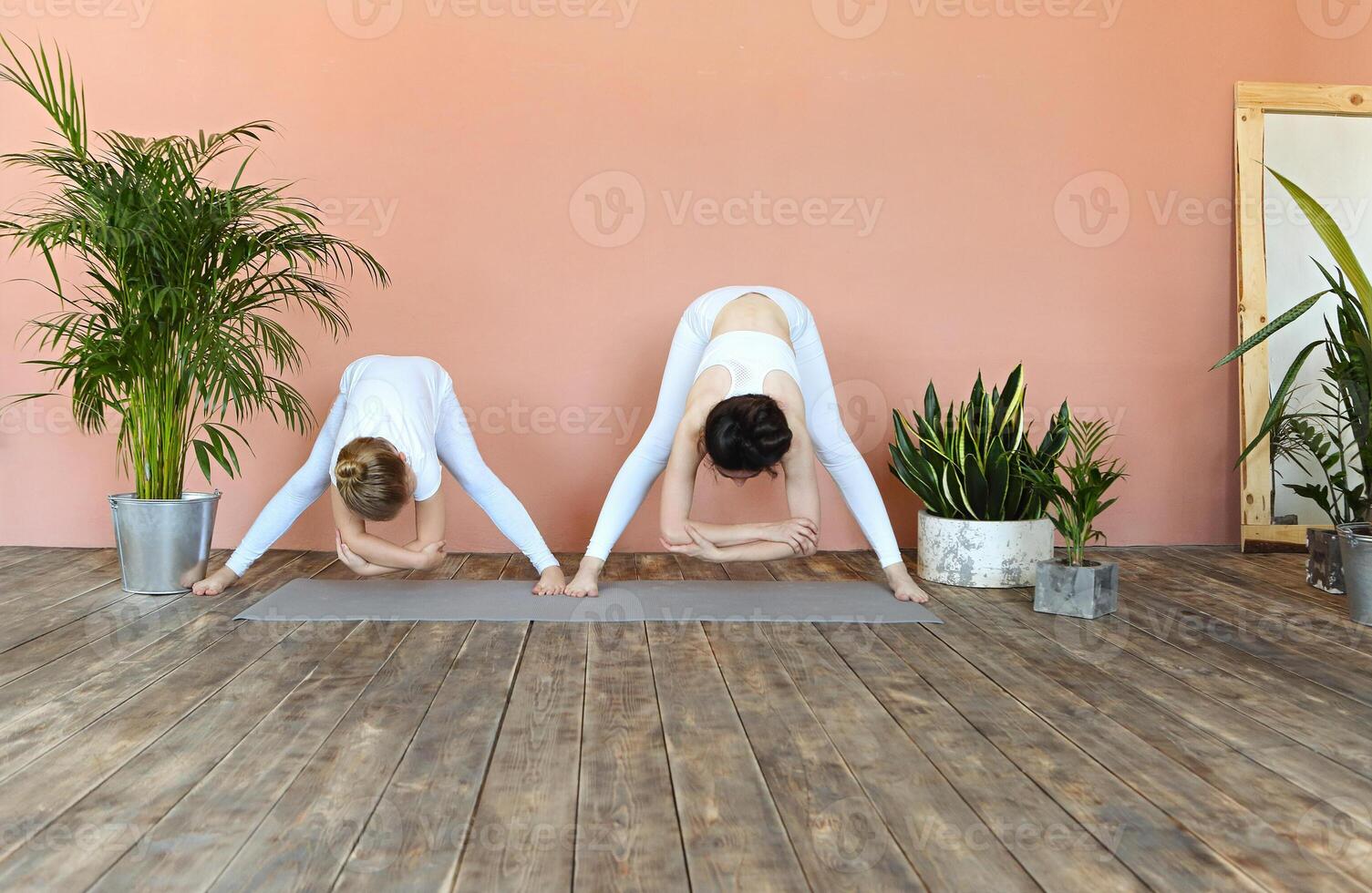 Smiling mother and daughter practicing yoga together photo
