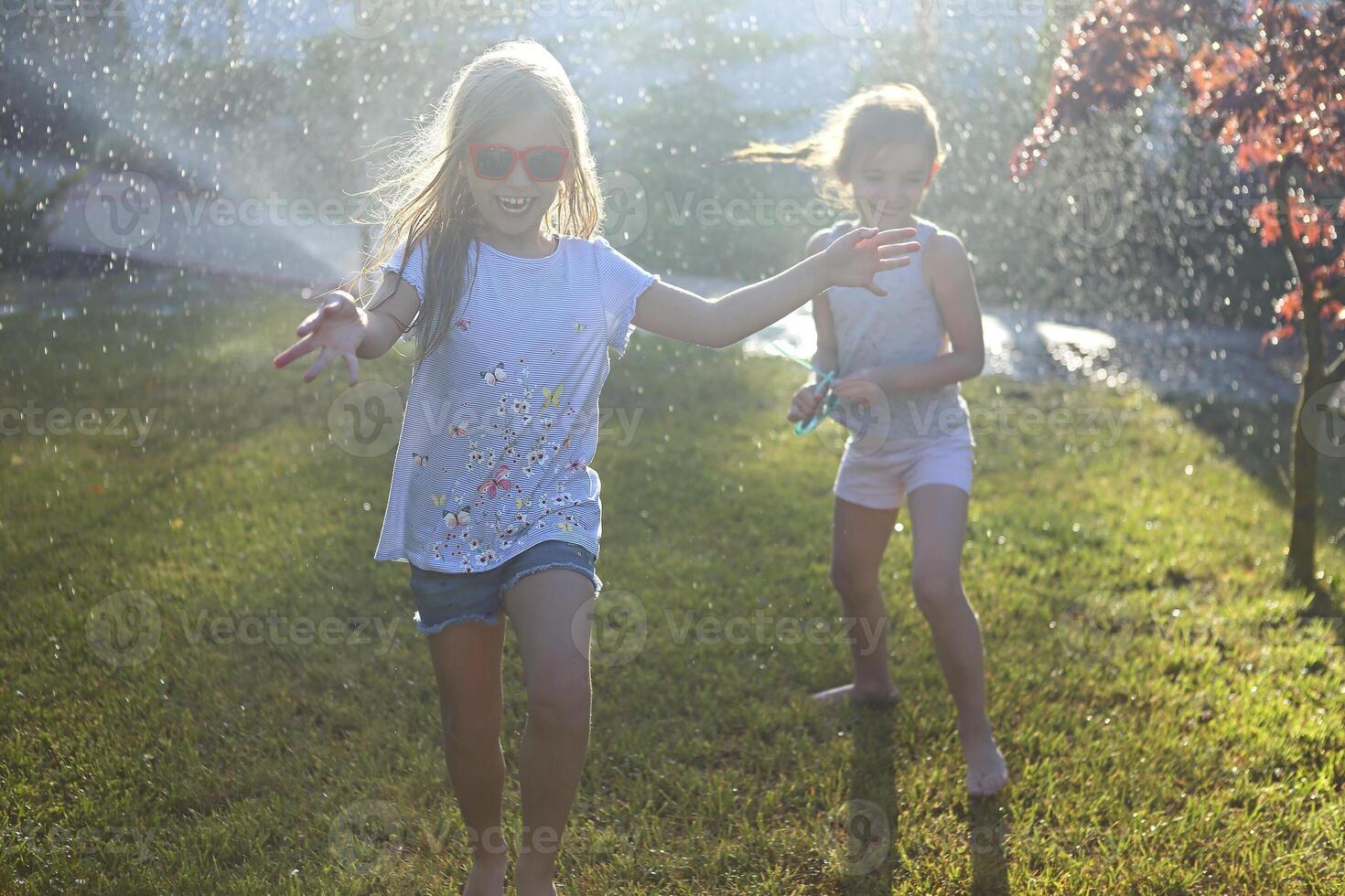 Child playing with garden sprinkler. Kids run and jump. Summer outdoor water fun in the backyard. Child playing with garden sprinkler. Kids run and jump. Summer outdoor water fun in the backyard photo
