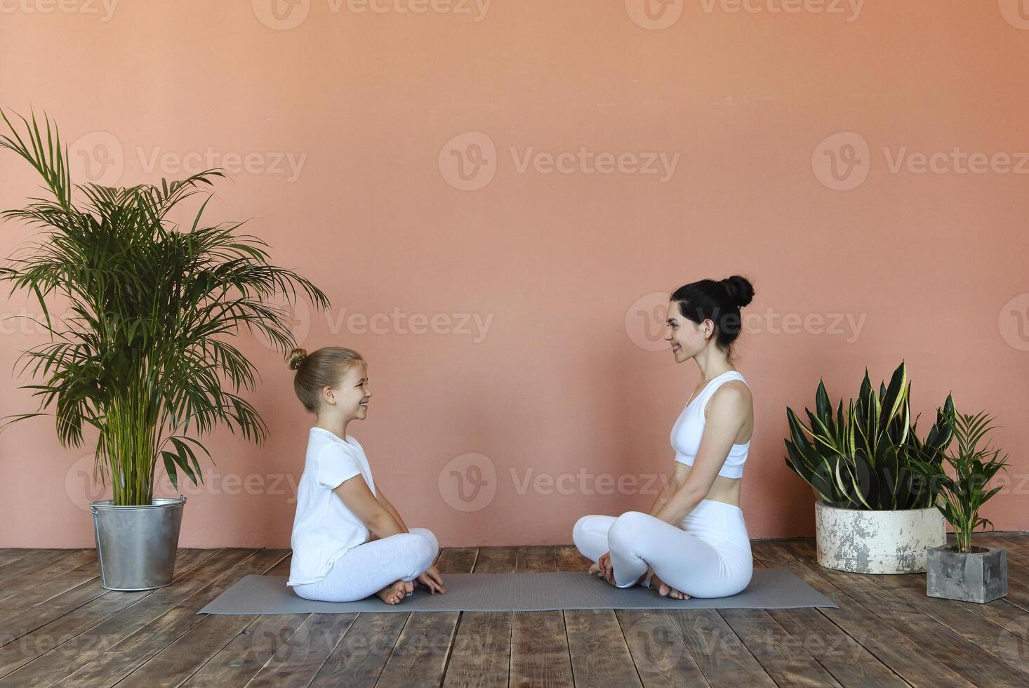 Smiling mother and daughter practicing yoga together photo