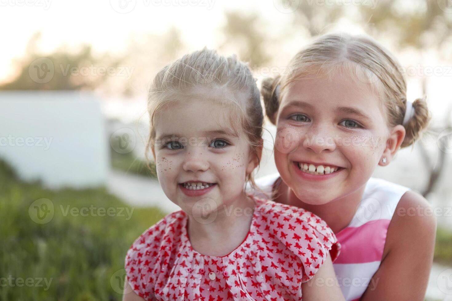Happy blond haired girls sisters with freckles gold laughing and hug photo