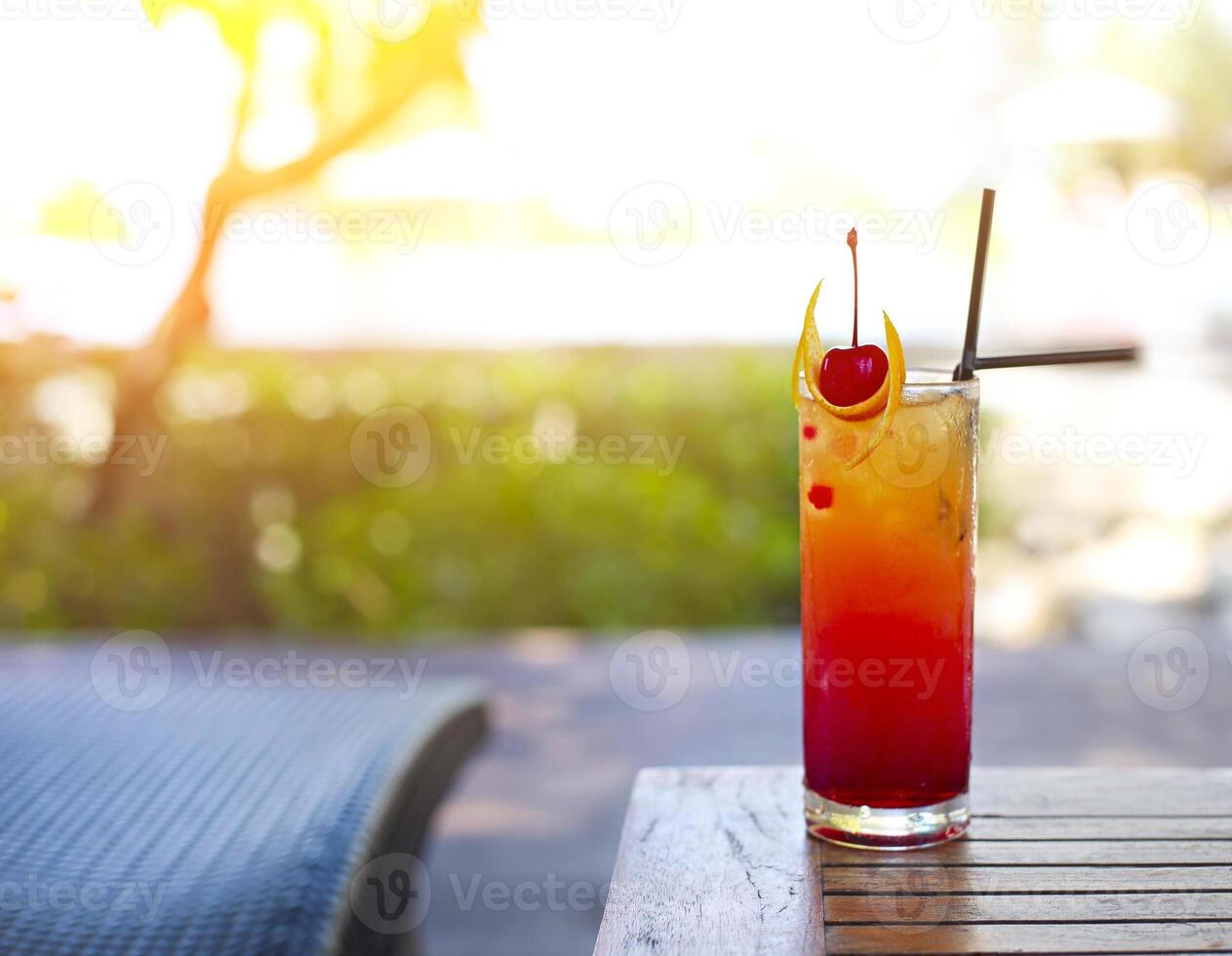 Glass with a bright tequila sunrise cocktail by the pool photo