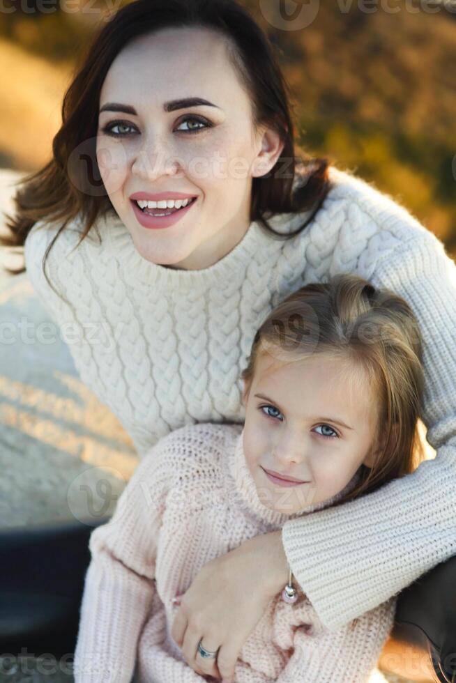 Young mother and her little daughter outdoors on sunny autumn day photo