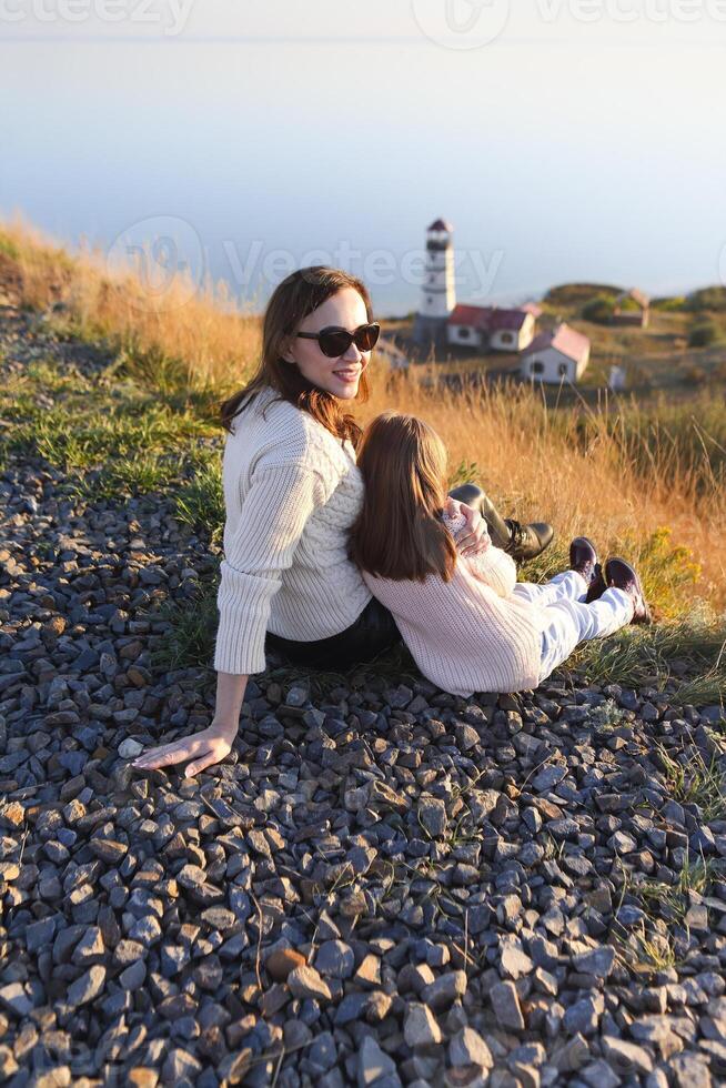 Mother and little daughter dressed in cozy sweaters together near the lighthouse photo