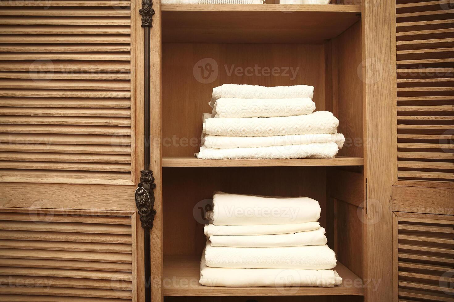 Stacks of clean white soft towels in cupboard in room photo