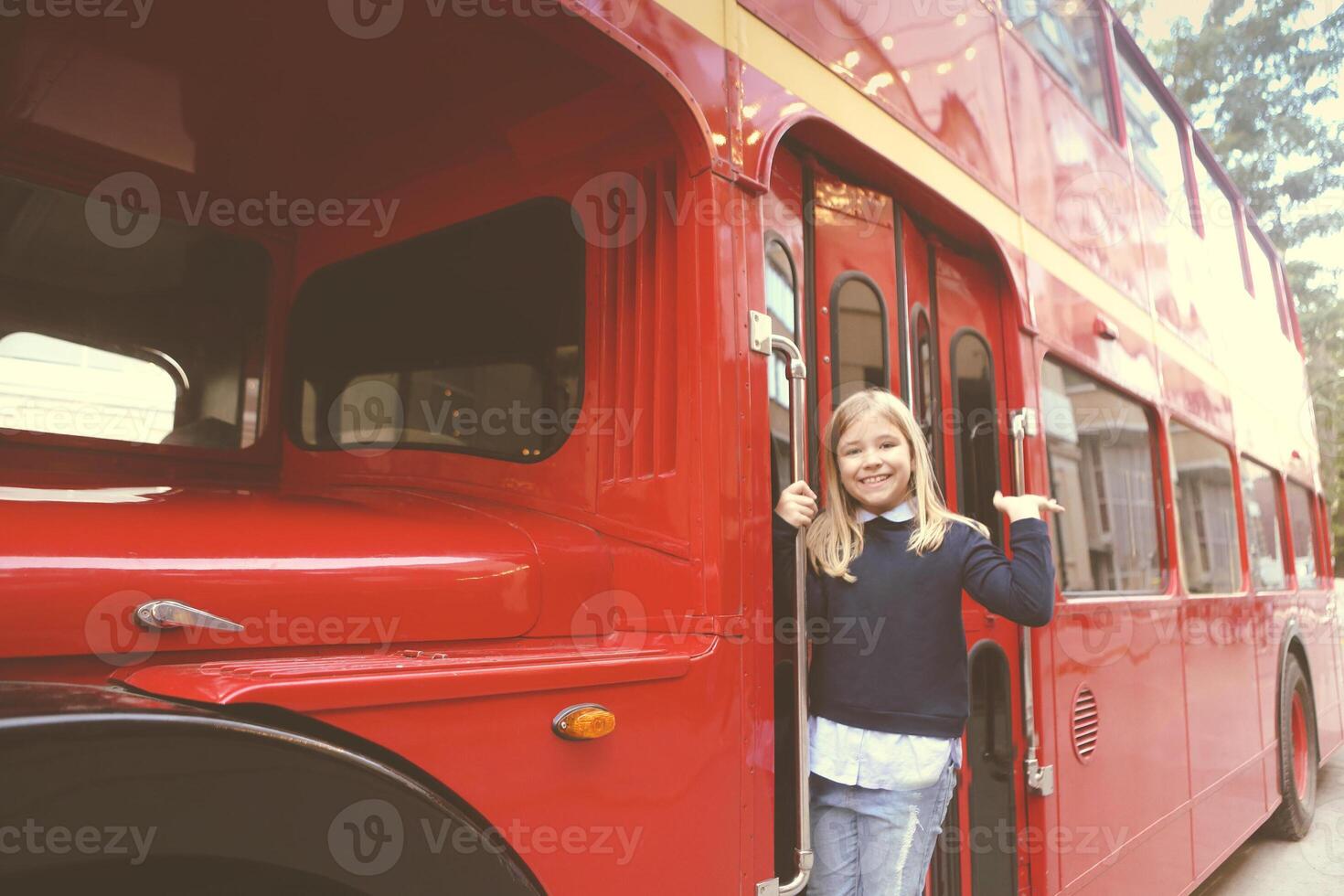 Preteen girl in entrance of red bus photo