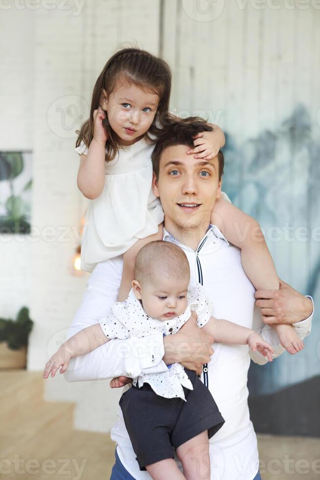 Portrait of a happy young father with a baby son and little daughter at home photo