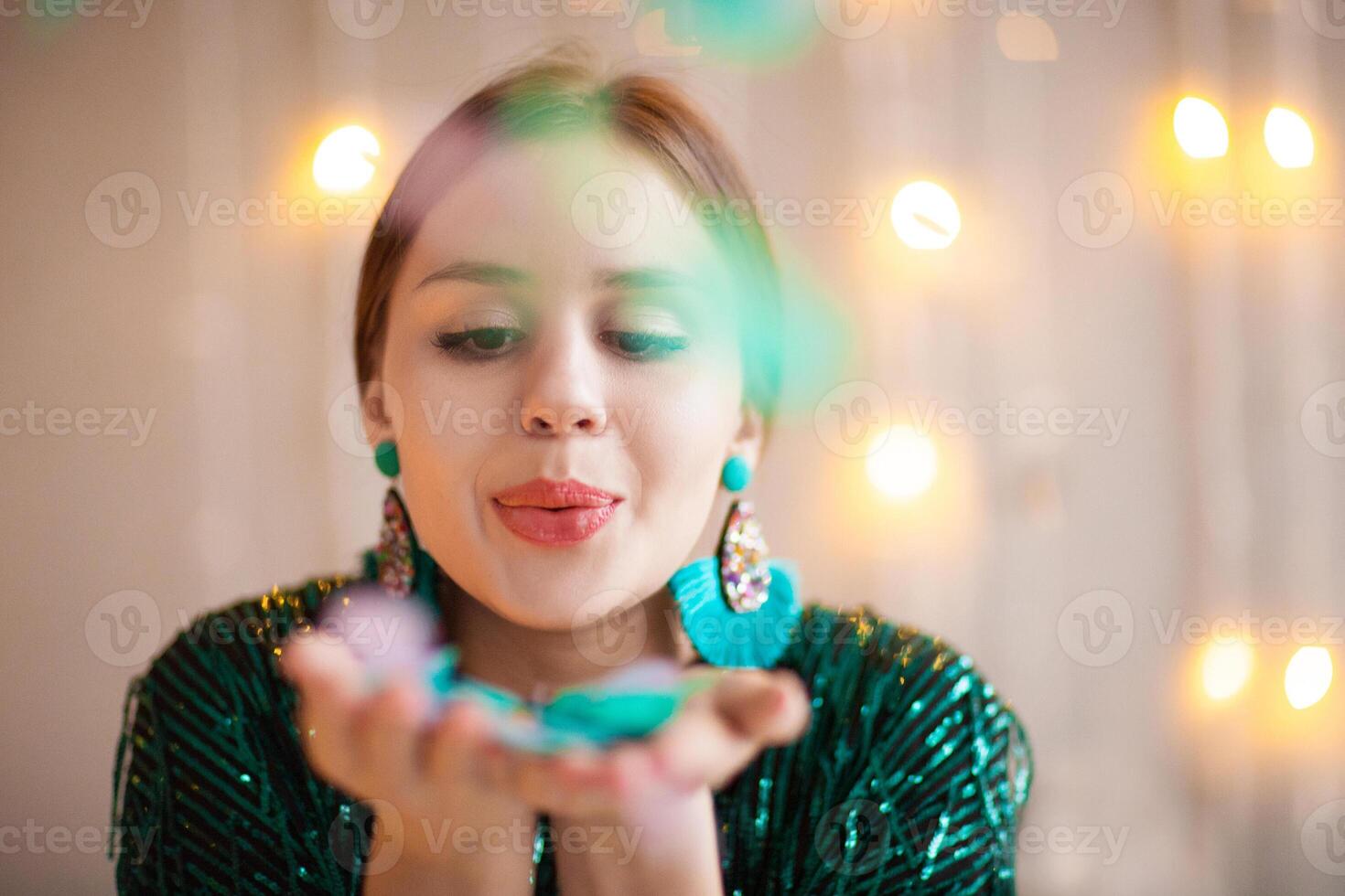 Cheerful woman blowing Christmas confetti photo