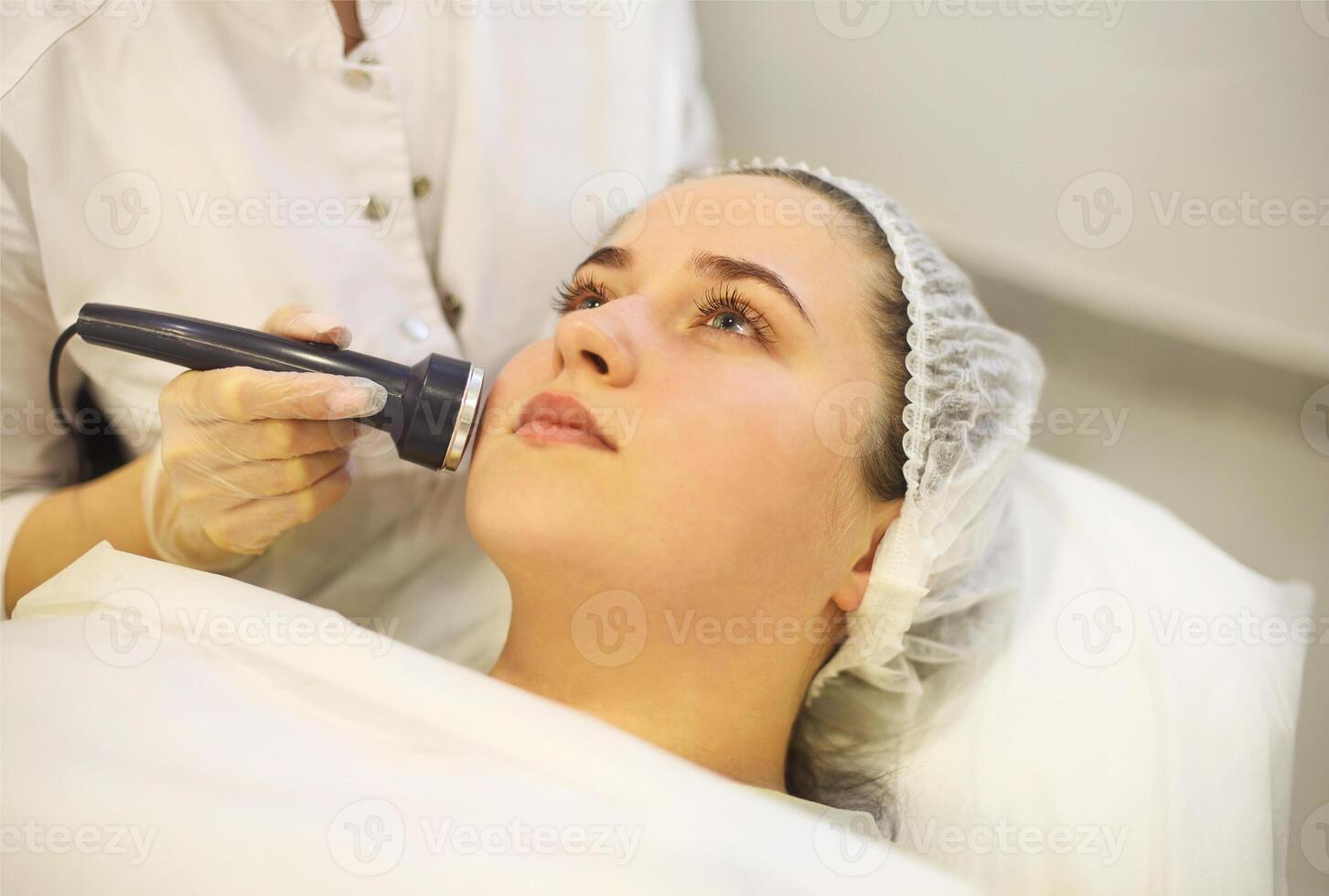 Crop beautician using machine for radiofrequency lifting photo