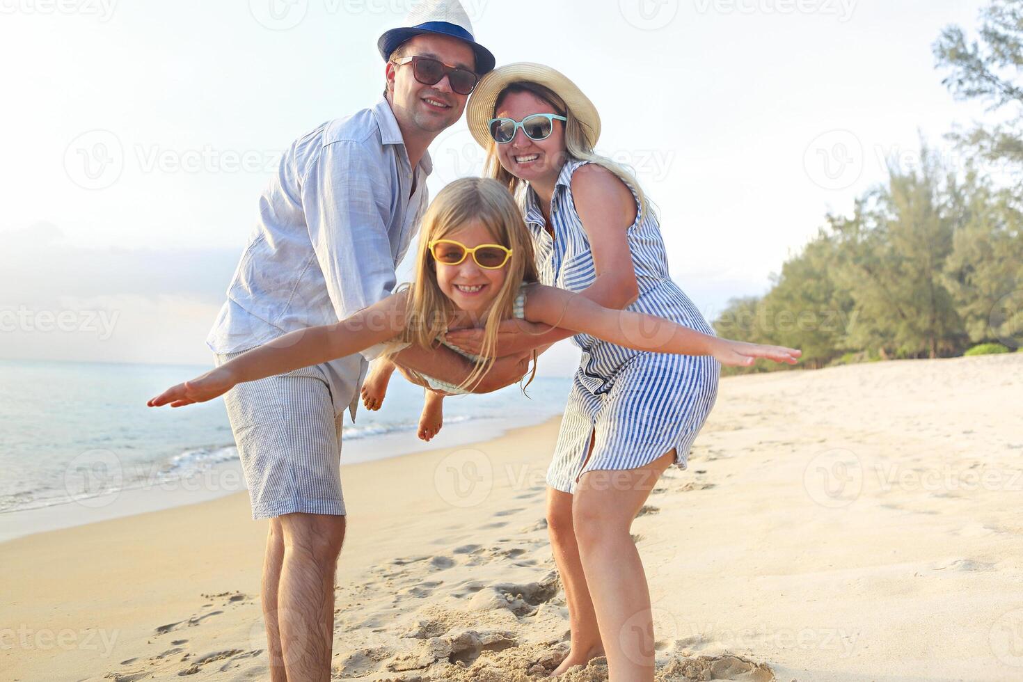 Happy family on the beach. People having fun on summer vacation. Father, mother and child against blue sea and beach background. photo