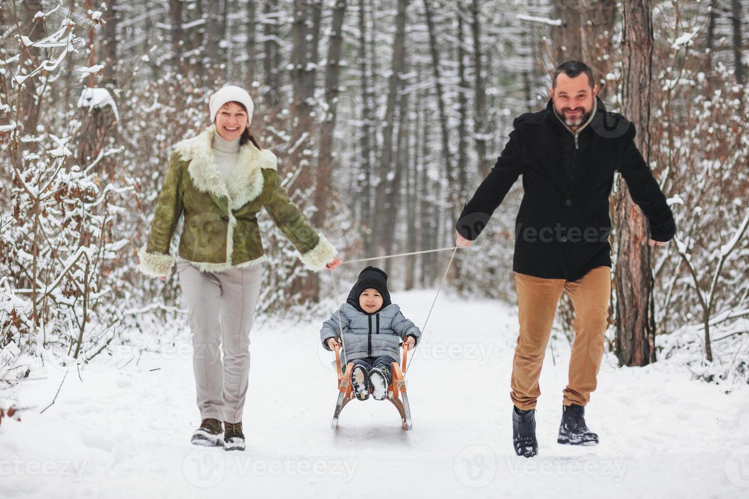 Happy family walking in winter forest photo