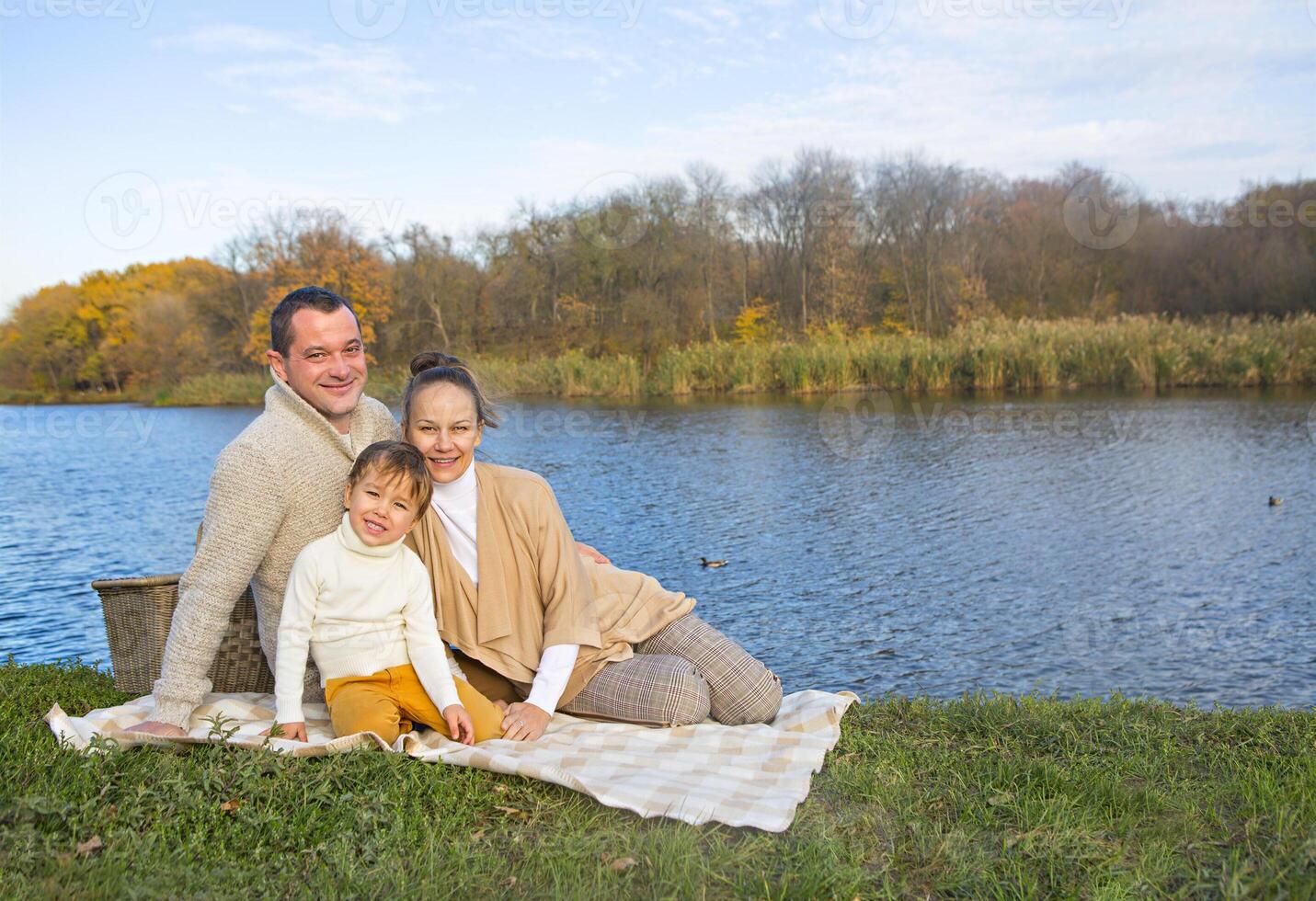 Young family resting on the lake shore photo