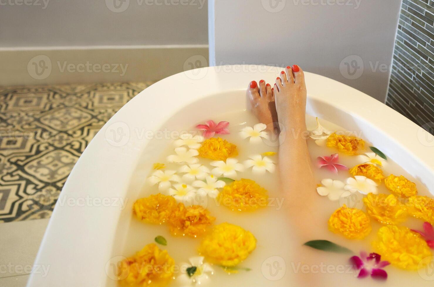 Young woman in bath with milk and flowers photo