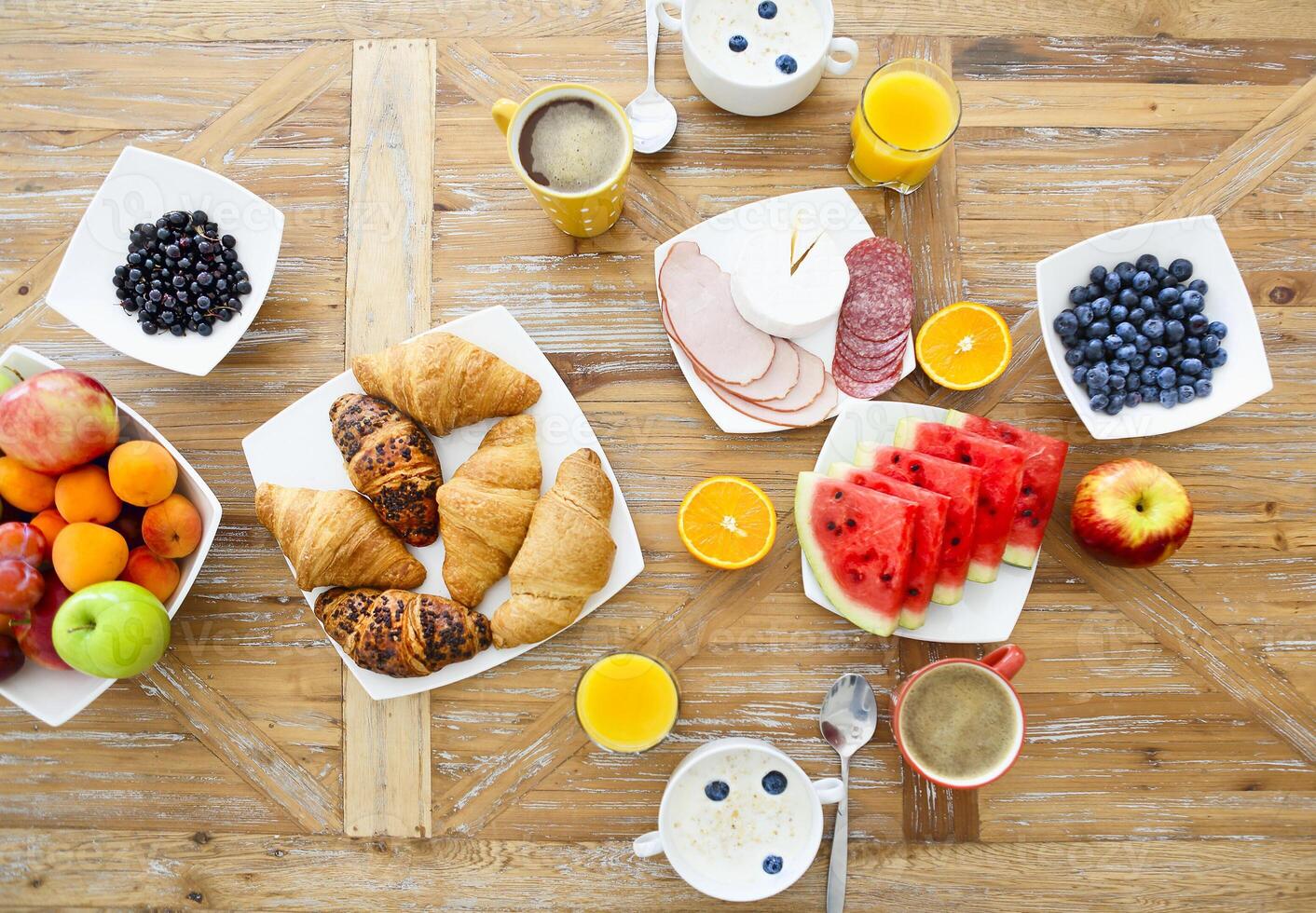Coffee with fruit, cereal and croissant on wooden table background photo