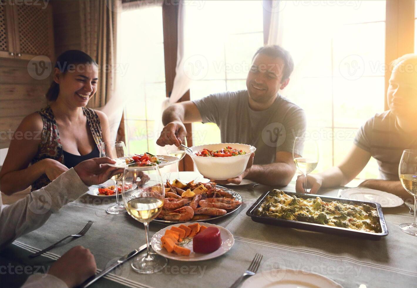 Table with white wine, shrimps, salad and graten photo