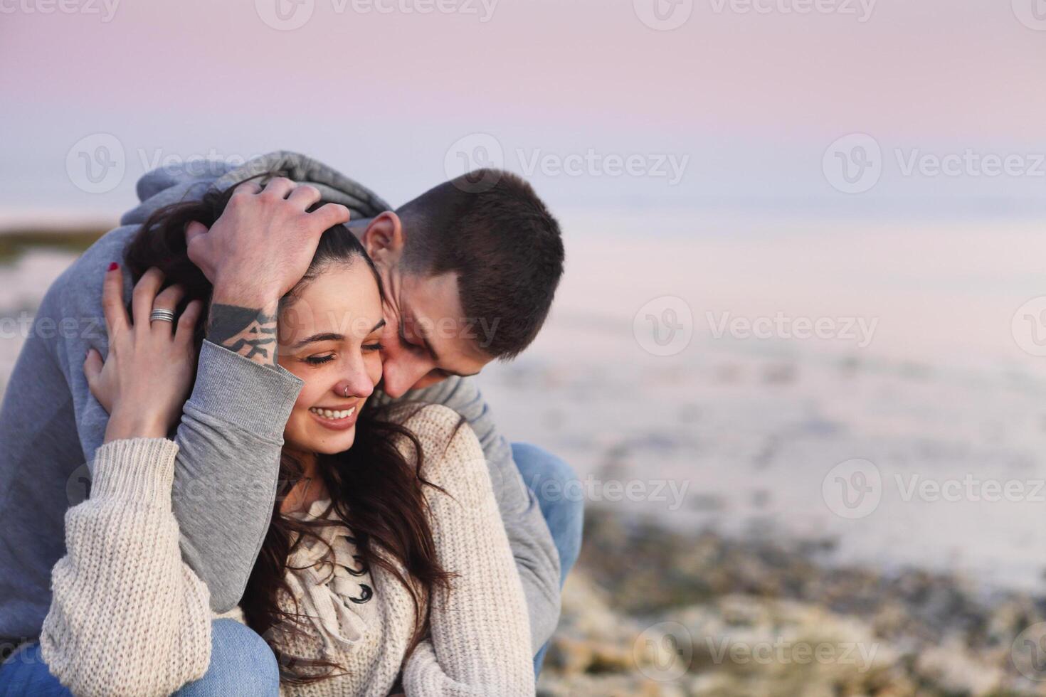 Young couple at rocky seacoast in sunset photo