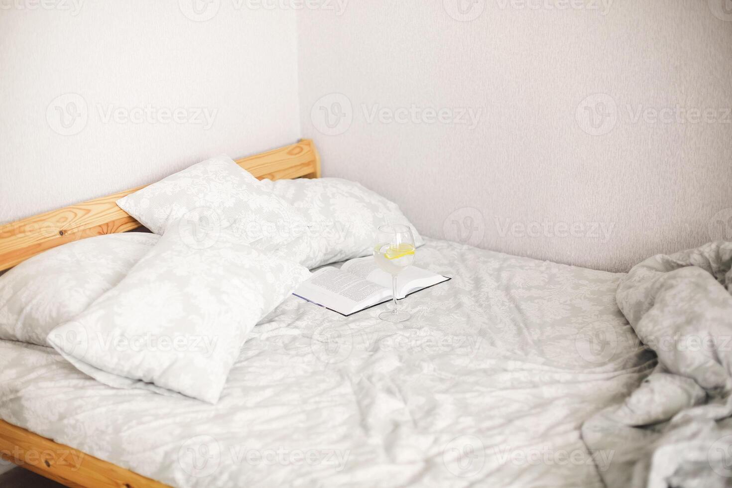 Side view of morning bed after awakening with open book and glass of lemon water photo