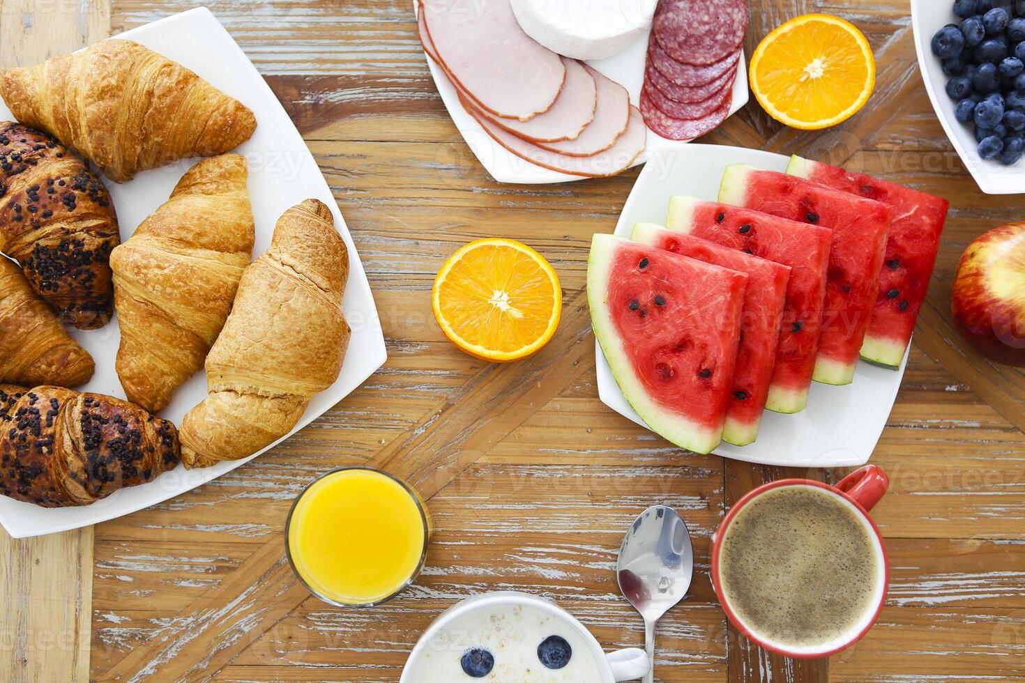 Coffee with fruit, cereal and croissant on wooden table background photo