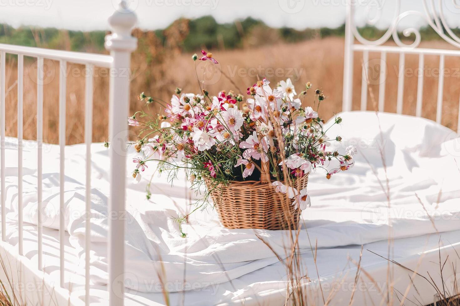Wicker basket of wildflowers on bed in middle of grain field photo