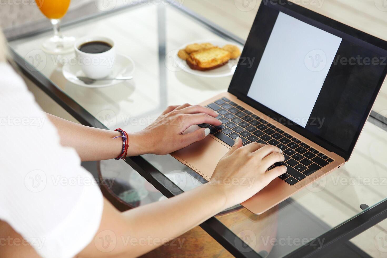 Woman drinking a coffee and using her laptop in the living room photo