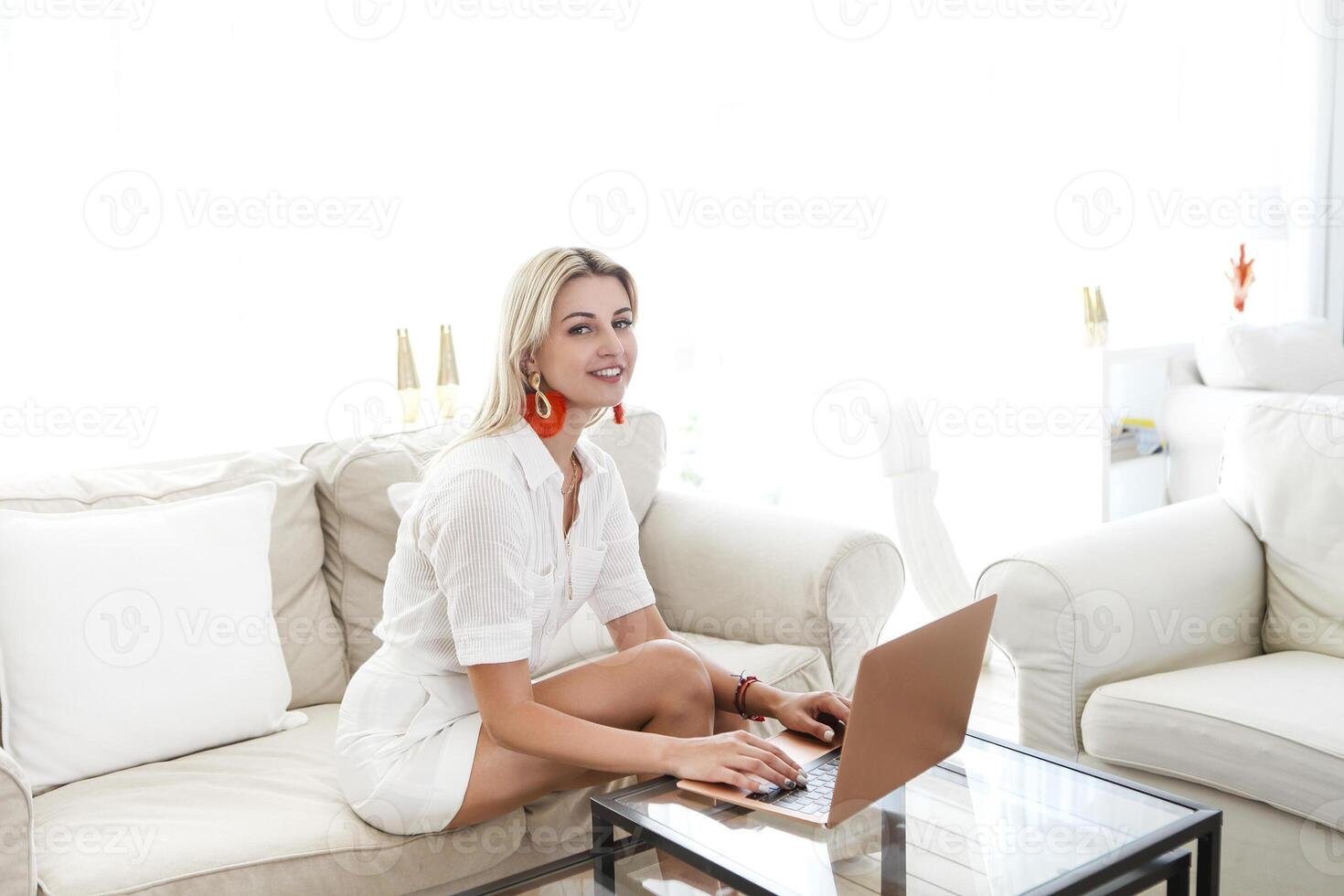 Woman drinking a coffee and using her laptop in the living room photo