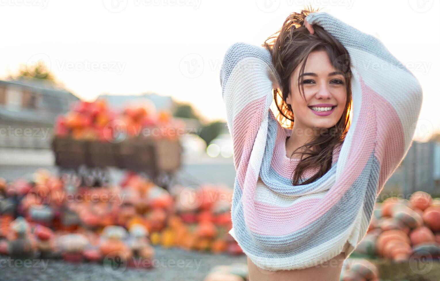 Fashionable beautiful young girl at the autumn pumpkin patch background. Having fun and posing photo