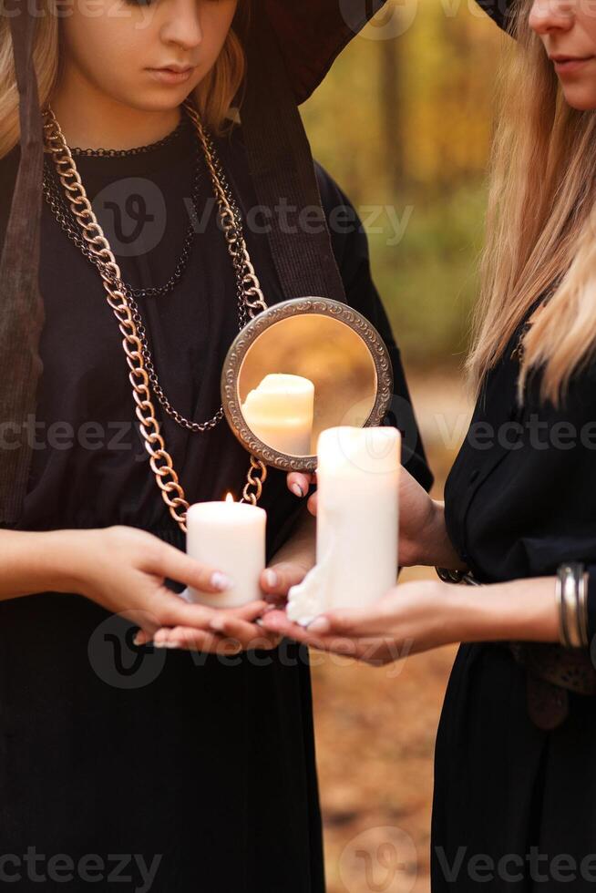 Two young women in Witch costume and hat looking mysteriously at candles photo