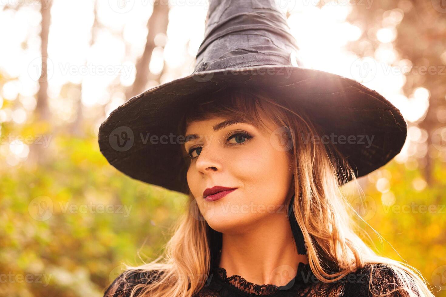 Young witch with jack o lantern in forest photo