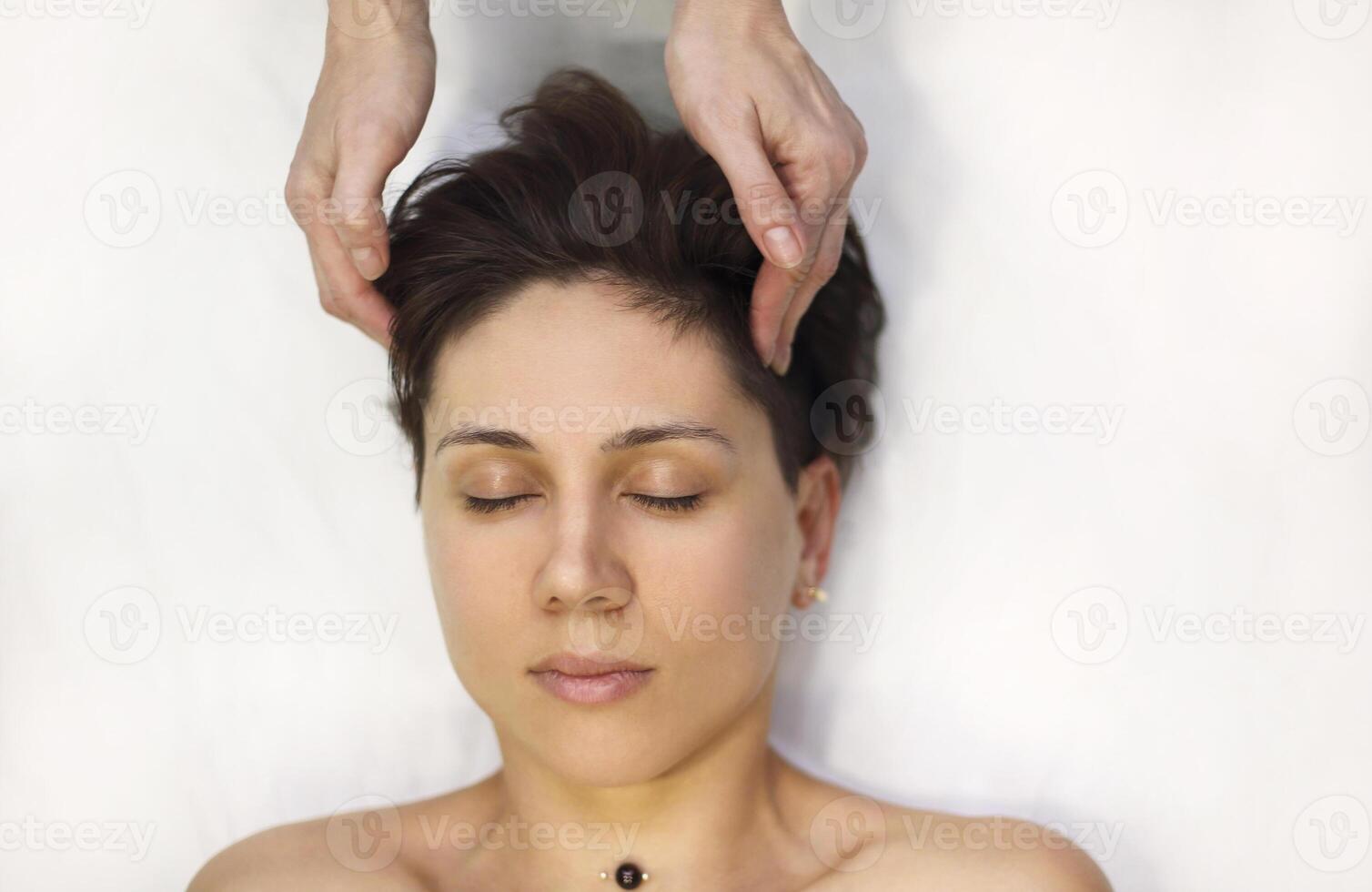 Crop massage therapist massaging face of client photo