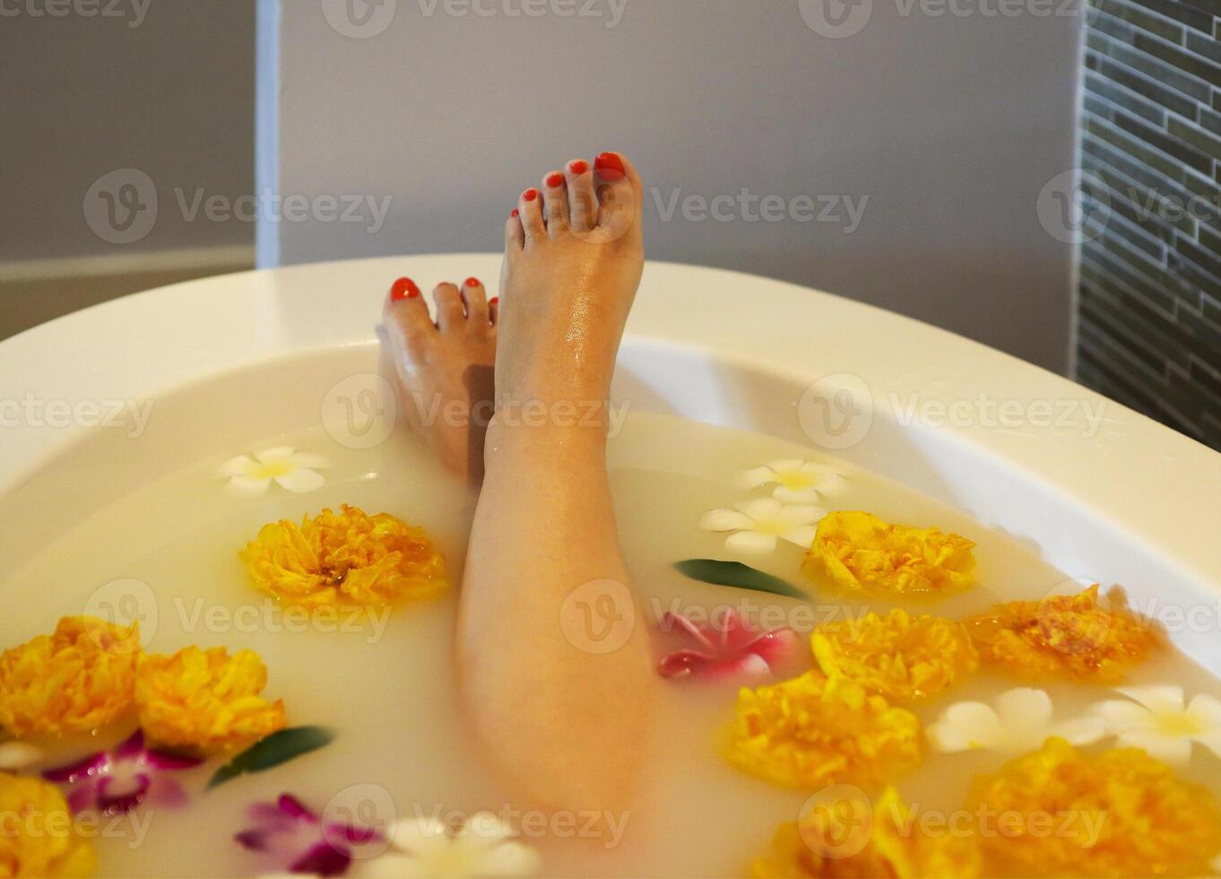 Young woman in bath with milk and flowers photo