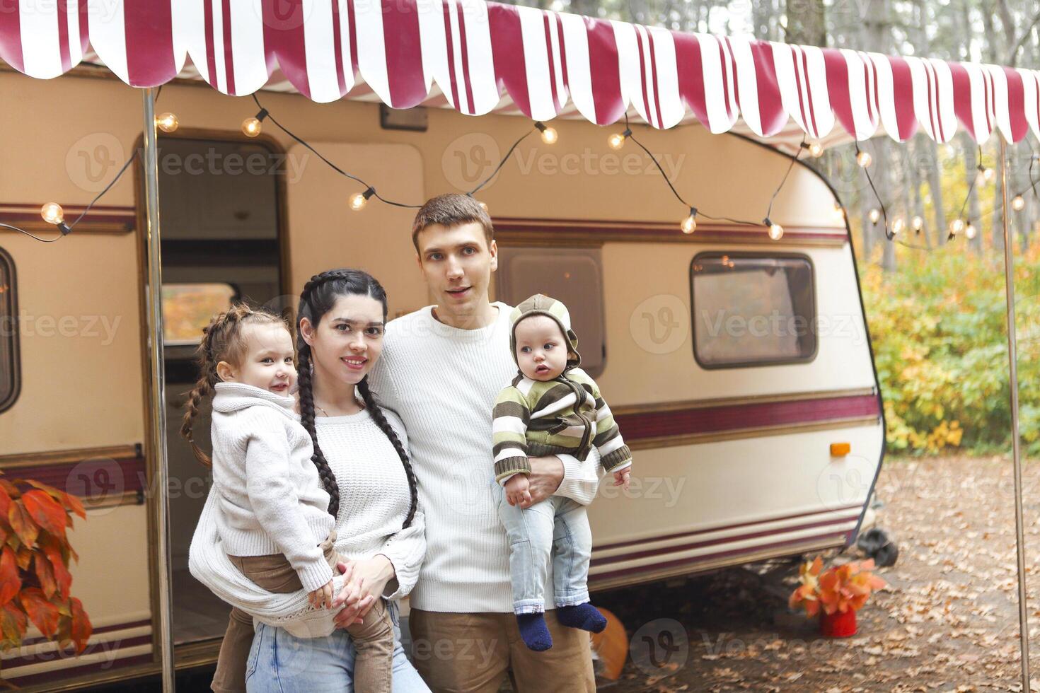 Portrait of a young smiling family while hugging near house on wheels photo