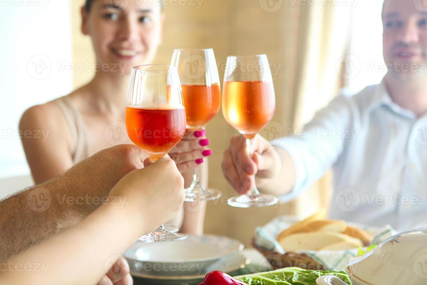 Closeup of four glasses with rose wine being clinked together photo