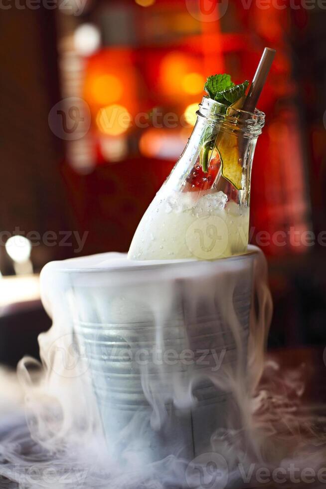 Lemonade serviced in the bottle with mint in the bucket with dry ice photo