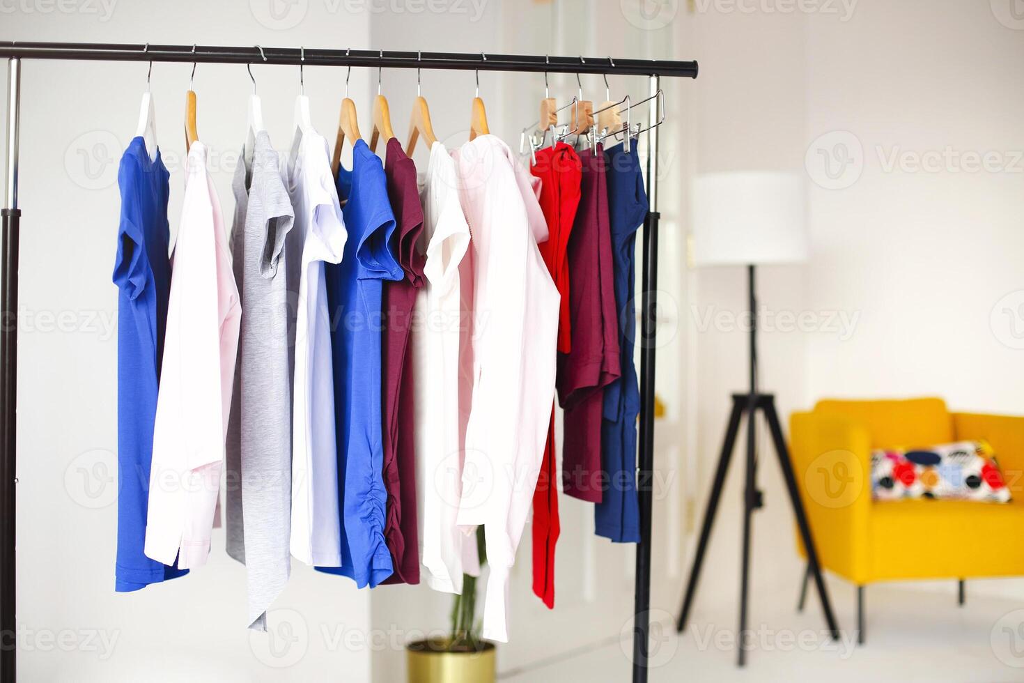 Colorful clothes hanging on rack in room photo