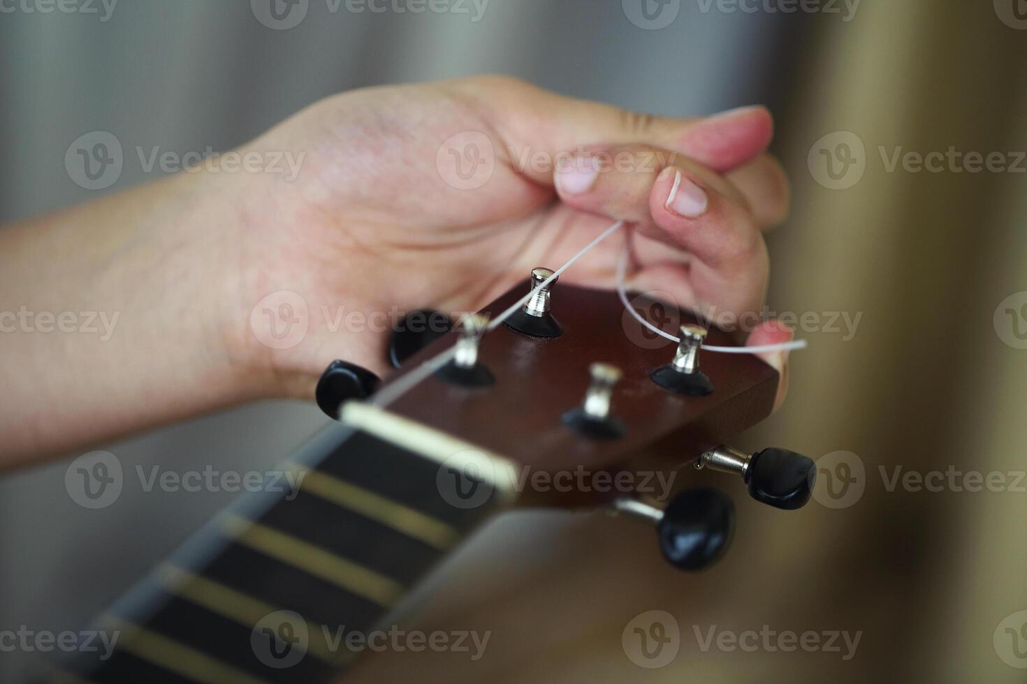 Tuning the string of ukulele, human hands, closeup photo