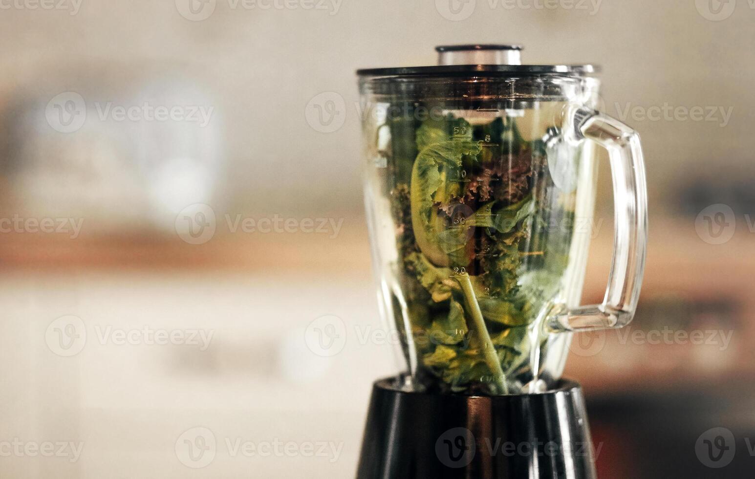 Green vegetable smoothie blender machine in kitchen with kale leaves inside photo