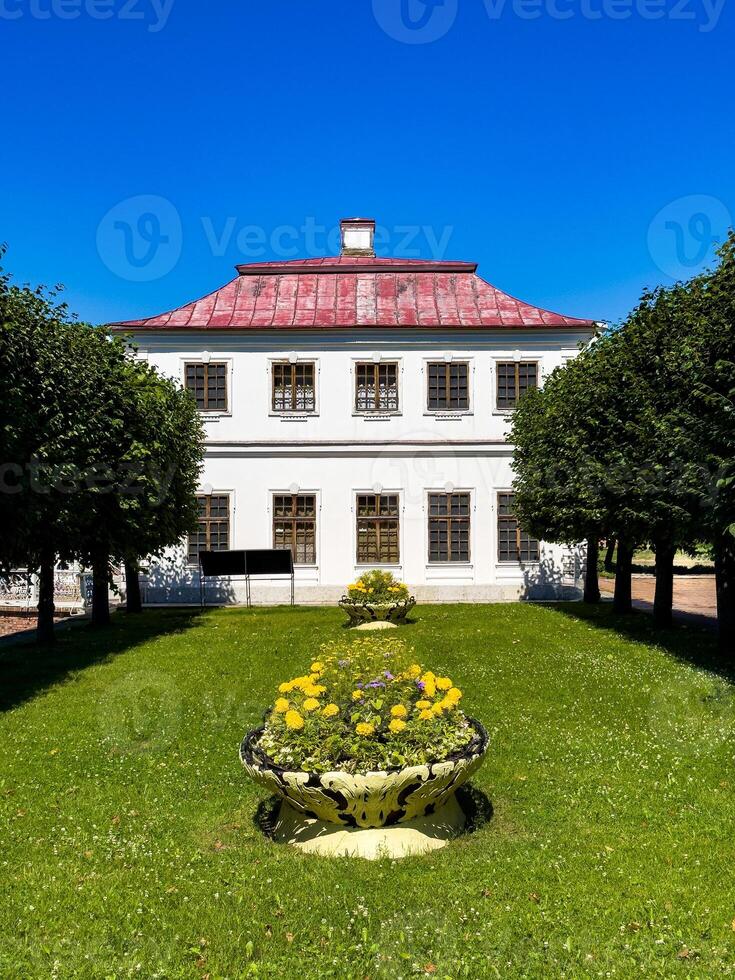 Elegant view of a manicured garden featuring symmetrical rows of trees and a historic building, surrounded by lush greenery and vibrant blue skies, highlighting the harmony of nature and architecture. photo