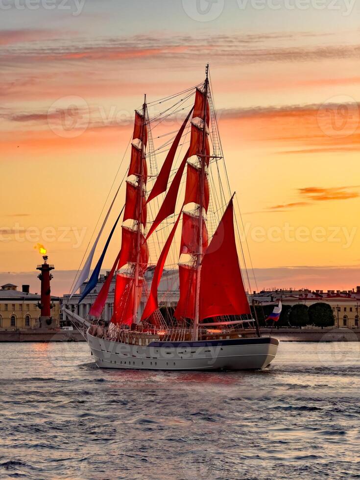 A breathtaking view of a majestic ship with vibrant red sails gliding along the Neva River during sunset in St. Petersburg, Russia. photo