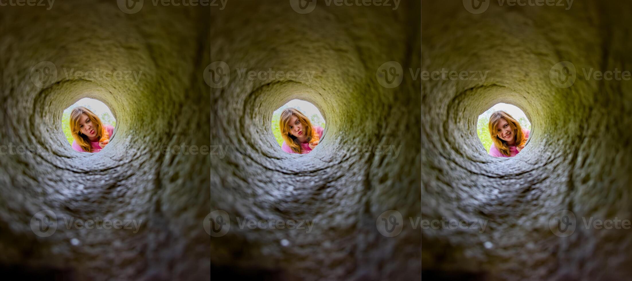 A young girl peers down a hole in granite, her face framed by the rugged stone. Her curious expression and the unique perspective create an engaging and playful scene, perfect for illustrating curiosity, exploration, and childhood adventures. photo