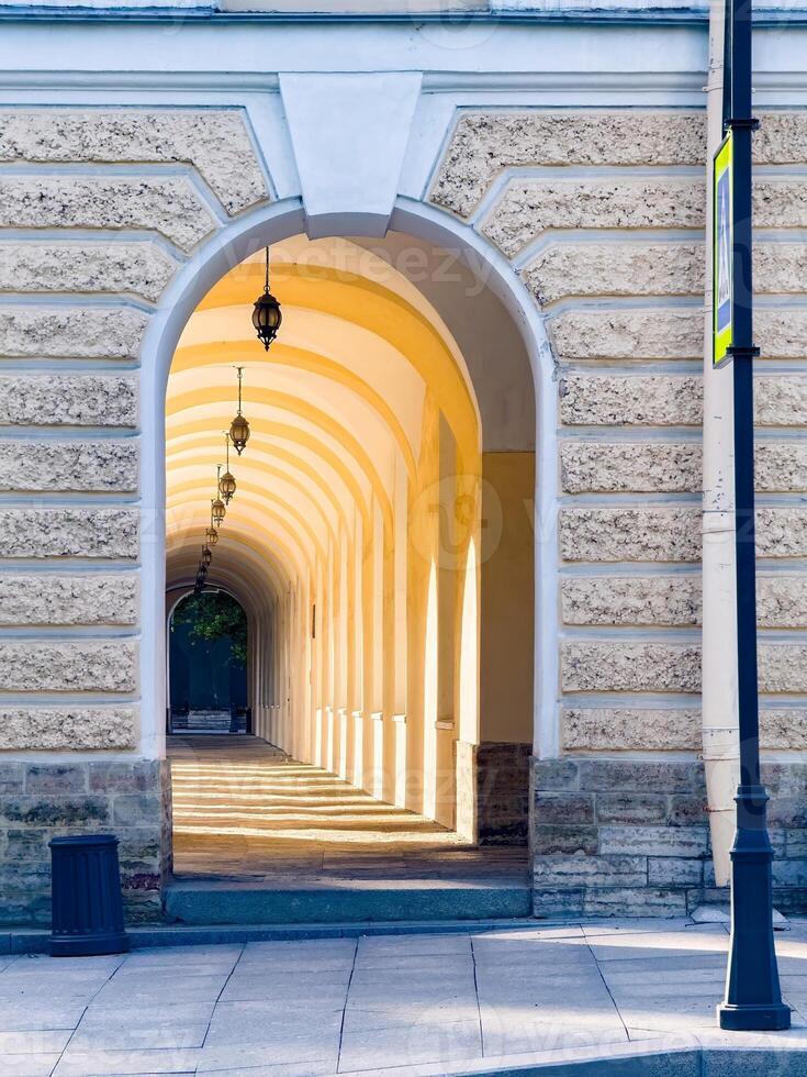 Beautifully lit archways of a historic building in St. Petersburg, Russia. The serene morning light highlights the architectural details and symmetry, creating a captivating urban scene photo