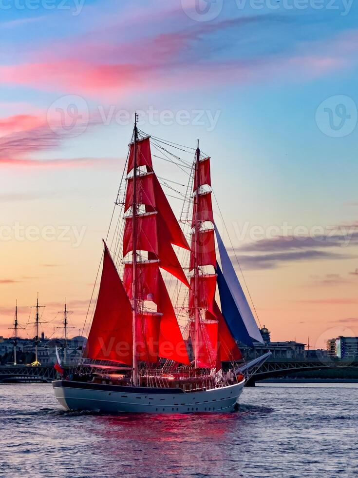 A breathtaking view of a majestic ship with vibrant red sails gliding along the Neva River during sunset in St. Petersburg, Russia. photo