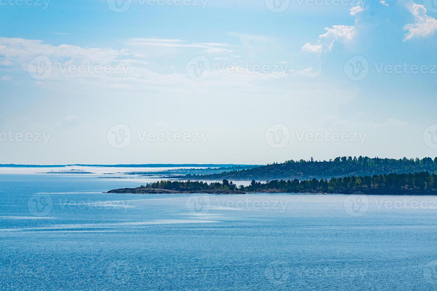 A picturesque forested island surrounded by the pristine blue waters of a tranquil lake. Perfect for nature and travel enthusiasts looking for a serene and natural landscape. photo