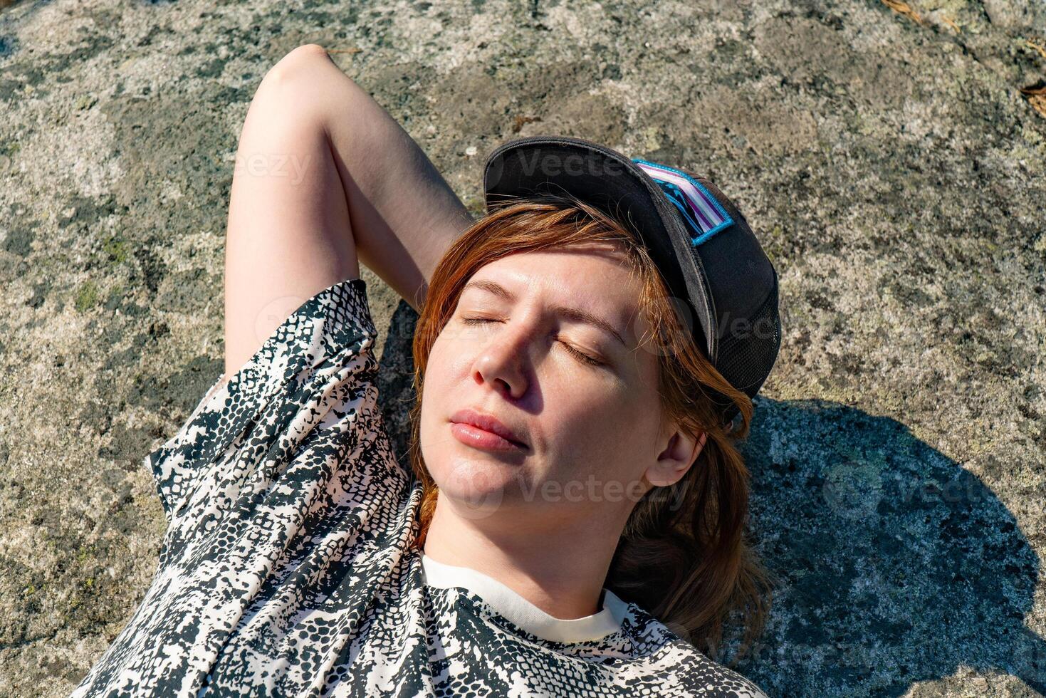 Close-up of a woman relaxing and smiling in a sunlit forest, showcasing her joy and serenity amidst nature. Ideal for themes of relaxation, nature, and outdoor lifestyle. photo