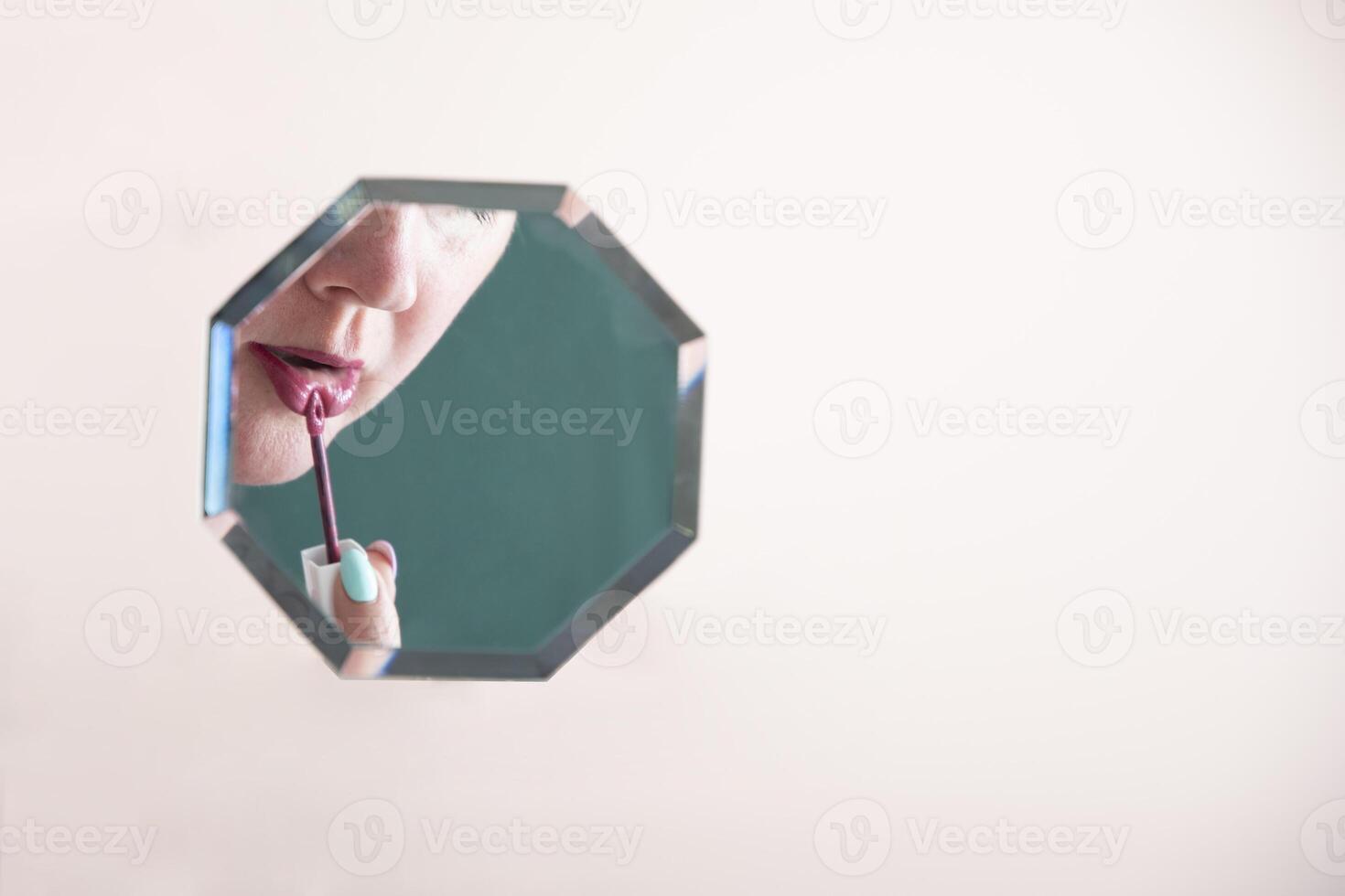 reflection of a woman in the mirror who paints her lips with lipstick, mirror hanging in zero gravity on peach fuzz background, photo