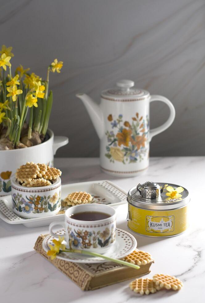 Still life with Kusmi tea and milk cookies on a table, vase with yellow spring daffodils, As, Belgium, February 23, 2021 photo